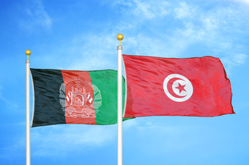 Afghanistan and Tunisia  two flags on flagpoles and blue cloudy sky