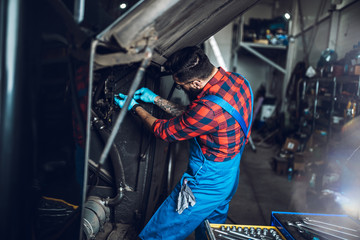 Fototapeta na wymiar Professional car mechanic working in vehicle repair service.