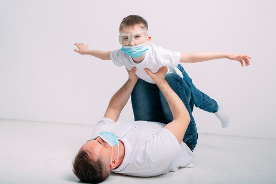 Father and son play during quarantine in medical masks.
