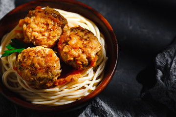 Spaghetti pasta with meatballs in white sauce with carrots and onions. On a rustic wooden plate. Top view, side view. Place for the label.