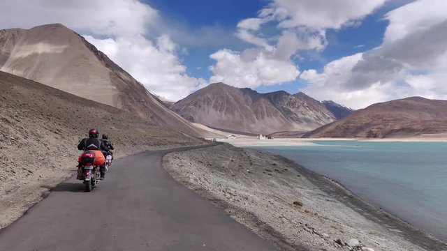 Two bikers riding alongside the famous Pangong Lake in Ladakh, India.
