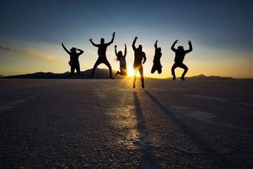 Silhouettes of six jumping people at sunset in the salt flats of Salar de Uyuni, Bolivia