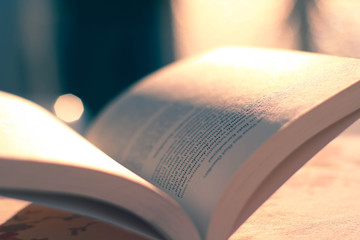 offenes Buch Das Buch liegt deutlich auf dem Tisch und das Sonnenlicht scheint von hinten