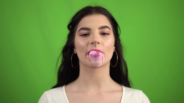 Sexy beauty girl blowing cheving bubble gum on green screen