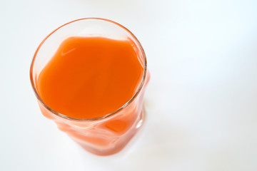 fresh carrot juice in a glass over white