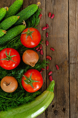 Fresh rustic vegetables on an old wooden table - tomatoes, cucumbers, onions, dill, beans.