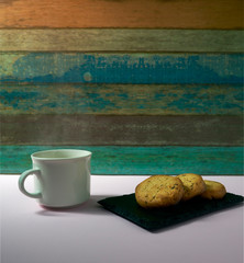 
Homemade butter cookies and a white cup on a pink table and wooden background. The image has space for a text.