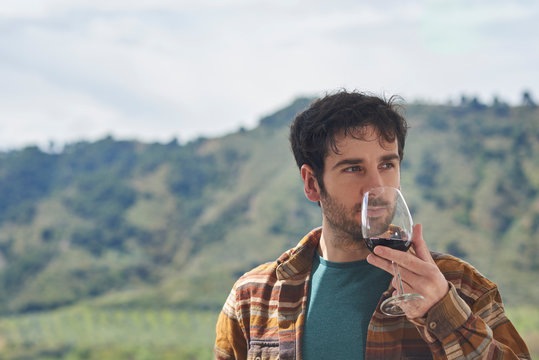 
Man tastes a glass of red wine on a terrace with a view. The image has space for a text.