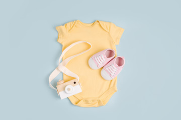 Yellow cute baby bodysuit with toy. Set of kids clothes and accessories. Fashion newborn. Flat lay,...