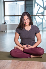 Photo of young woman practicing yoga indoor. Beautiful girl practice yoga in class. Yoga studio instructor. Blurred background.