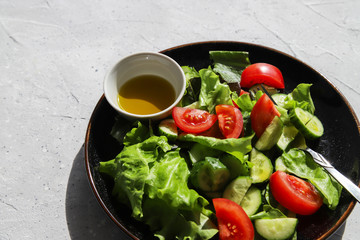 Fresh summer vegetable salad with tomatoes, cucumber, lettuce and olive oil. Healthy food for vegetarian or vegan