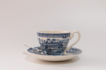 Coffee cup with saucer and teaspoon, patterned in blue tones, vintage style, on white background