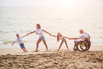Fototapeta premium Disabled man in a wheelchair with his family on the beach.