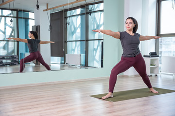 Photo of young woman practicing yoga indoor. Beautiful girl practice yoga in class. Yoga studio instructor. Blurred background.