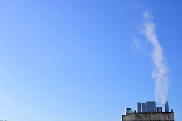 Big chimney throwing smoke to the blue sky