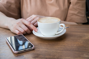 On the table a woman's hand, a Cup of coffee and phone. Mock up. Cooking, food delivery, cafe, restaurant, cheese Factory, cheese tasting