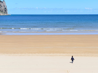 Figure of a boy running towards the sea on an empty beach