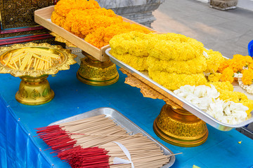 Garlands of orange and yellow chrysanthemum flowers with incense at a Buddhist temple, Bangkok,...
