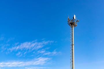 Communications tower with antennas against blue sky.