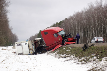 A trailer of a large car that fell on its side into a roadside ditch.