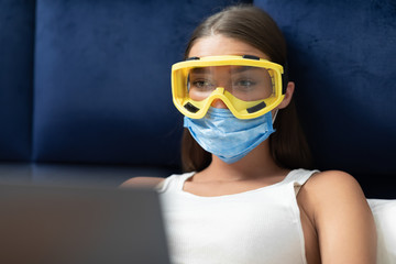 Girl Wearing Protective Mask Using Laptop Working Remotely In Bed