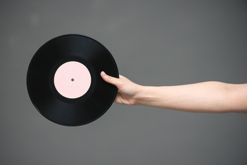 A vinyl record in singer hand on gray background.