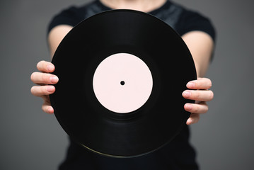 A vinyl record in singer hand on gray background.