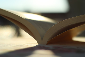 offenes Buch Das Buch liegt deutlich auf dem Tisch und das Sonnenlicht scheint von hinten