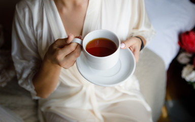 A young woman bride in a white coat holding a Cup of tea.