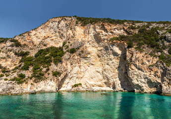 Natural cliff rocks reflected in blue water of Ionian sea in Summertime, Greece