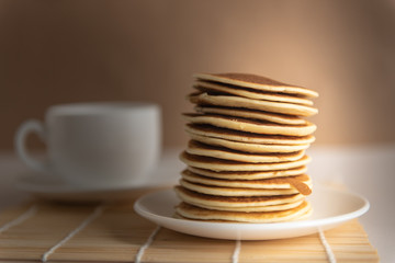 stack of pancakes on a white plate on craft background