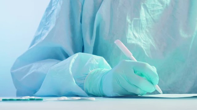 Coronavirus outbreak. Prescription drug. Nurse in protective equipment writing diagnosis.