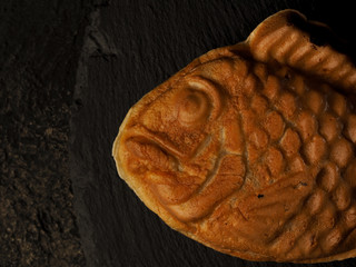 traditional japanese dessert tayaki. sweet waffles in the form of fish with different fillings. top view  a dark background. Black slate dishes