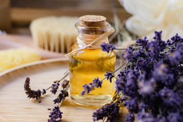 Concept of natural organic oil in cosmetology. Moisturizing skin care and aromatherapy. Gentle body treatment. Atmosphere of harmony relax. Wooden background, lavender flower, brush, soap. Close up
