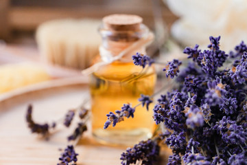 Obraz na płótnie Canvas Concept of natural organic oil in cosmetology. Moisturizing skin care and aromatherapy. Gentle body treatment. Atmosphere of harmony relax. Wooden background, lavender flower, brush, soap. Close up 