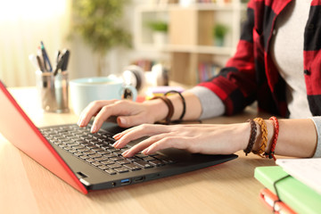 Student girl hands typing on red laptop at home