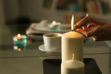 Woman hand lighting candles with lighter at night