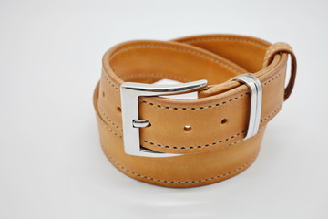 sample of brown leather men's belt with metal shiny handmade buckle, stitched on the edge, hand craft concept, white background,close up