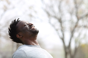 Happy black man breathing fresh air outdoors in winter