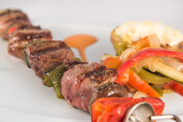 Skewer of iberian pork sirloin with vegetables and baked potato