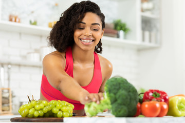 Happy young black woman preparing vegetable salad