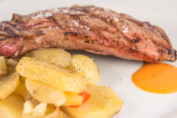 Dish of Iberian pork presa with baked potato slices.