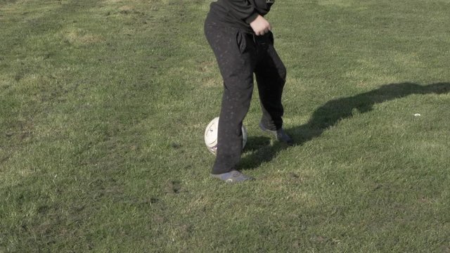 Boy on socks with a soccer ball, practicing soccer feints, slow motion