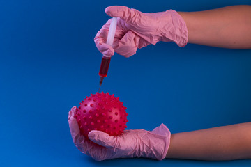 coronavirus vaccine. Syringe with a needle with a vaccine in hands in pink gloves from coronavirus on a blue background