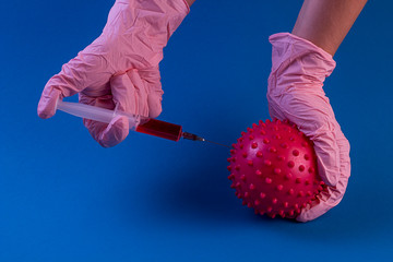 coronavirus vaccine. Syringe with a needle with a vaccine in hands in pink gloves from coronavirus on a blue background