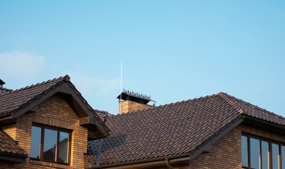 Brown natural tile roof. Modern types of roofing materials. Roof of the house, Natural roof tile against the blue sky. Building.