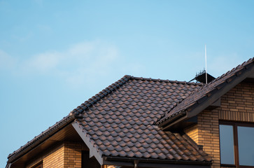 Brown natural tile roof. Modern types of roofing materials. Roof of the house, Natural roof tile against the blue sky. Building.