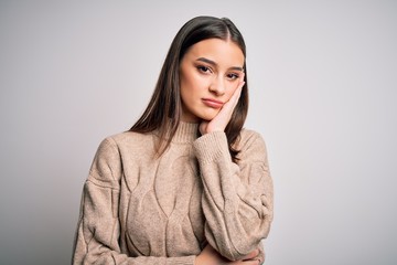Young beautiful brunette woman wearing casual sweater standing over white background thinking...