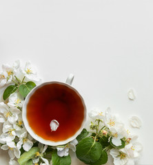 Spring breakfast. A cup of tea on the table and flowers of the apple tree.