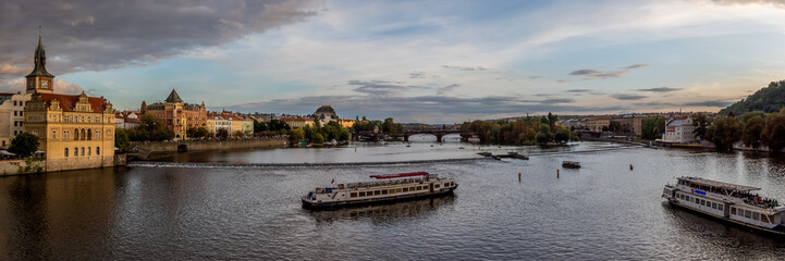 Fototapeta na wymiar Panoramic view of the Vltava River across to the national Theatre, with tourist boats crossing the river